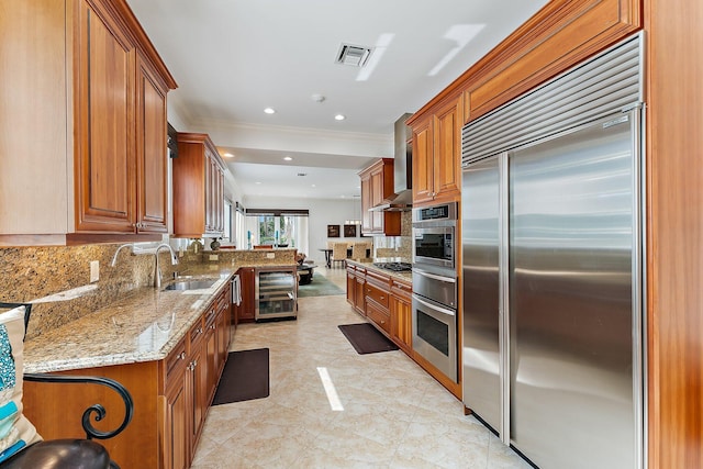 kitchen with tasteful backsplash, beverage cooler, stainless steel appliances, light stone countertops, and wall chimney range hood