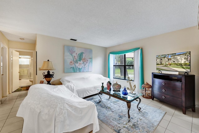 tiled bedroom with ensuite bath and a textured ceiling