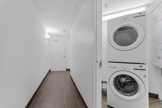 washroom featuring stacked washer and dryer and dark tile patterned flooring