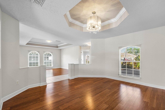 empty room featuring a raised ceiling, a textured ceiling, and hardwood / wood-style flooring