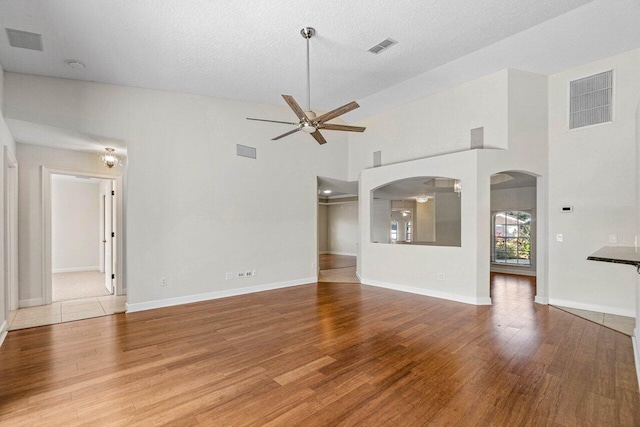 unfurnished living room with a ceiling fan, visible vents, and wood finished floors