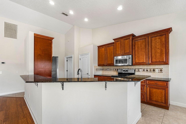 kitchen with visible vents, appliances with stainless steel finishes, and a breakfast bar