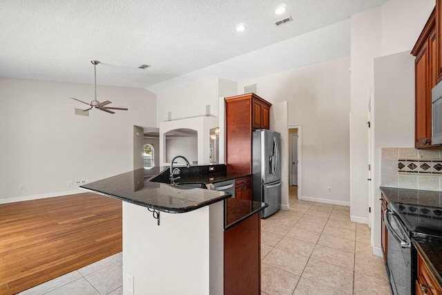 kitchen featuring light tile patterned floors, visible vents, arched walkways, a peninsula, and stainless steel appliances