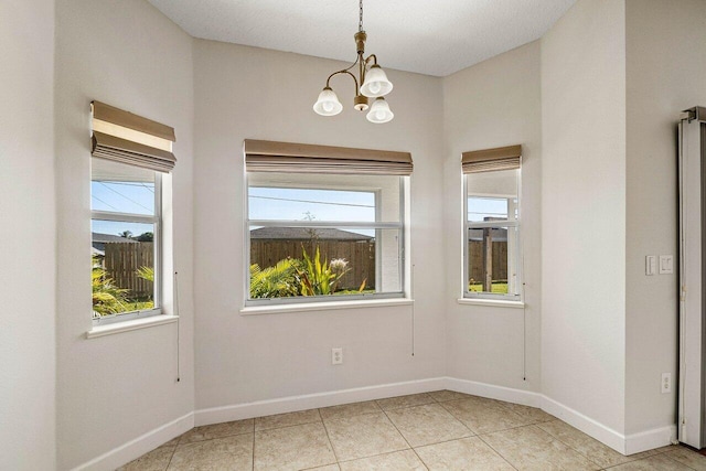 empty room featuring an inviting chandelier, baseboards, a wealth of natural light, and light tile patterned flooring