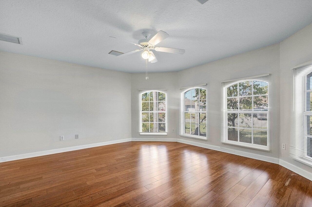 spare room featuring ceiling fan, hardwood / wood-style flooring, and a healthy amount of sunlight