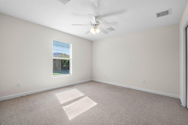 carpeted empty room with a textured ceiling, a ceiling fan, visible vents, and baseboards