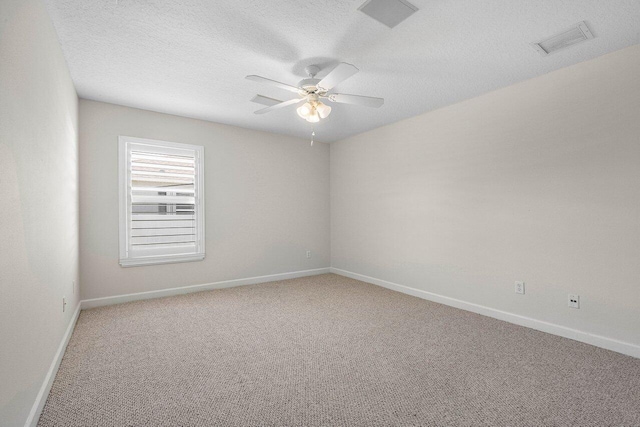 carpeted empty room featuring baseboards, a textured ceiling, visible vents, and a ceiling fan