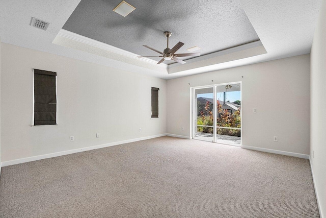 empty room featuring carpet floors, a tray ceiling, visible vents, and a textured ceiling