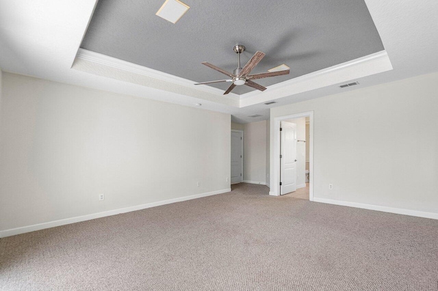 spare room featuring a raised ceiling, visible vents, light carpet, a textured ceiling, and baseboards