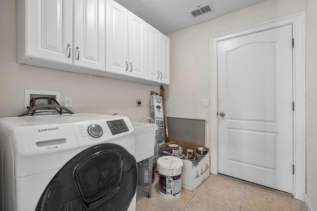 washroom featuring washer / dryer, cabinet space, visible vents, a textured ceiling, and light tile patterned flooring