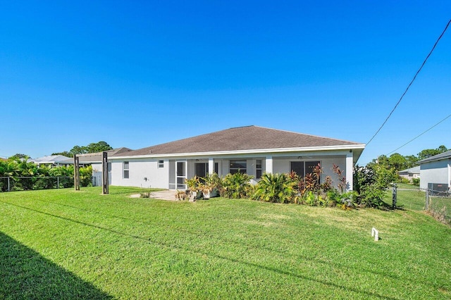 back of property featuring stucco siding, a yard, and fence