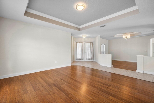 unfurnished room featuring ornamental molding, a raised ceiling, visible vents, and wood finished floors