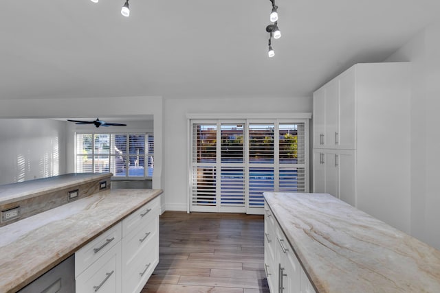 kitchen with white cabinetry, light wood-type flooring, ceiling fan, and light stone counters