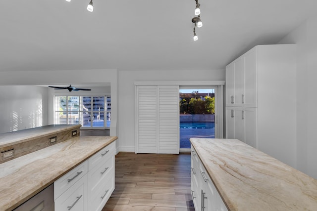 kitchen with ceiling fan, light stone countertops, light wood-type flooring, and white cabinets