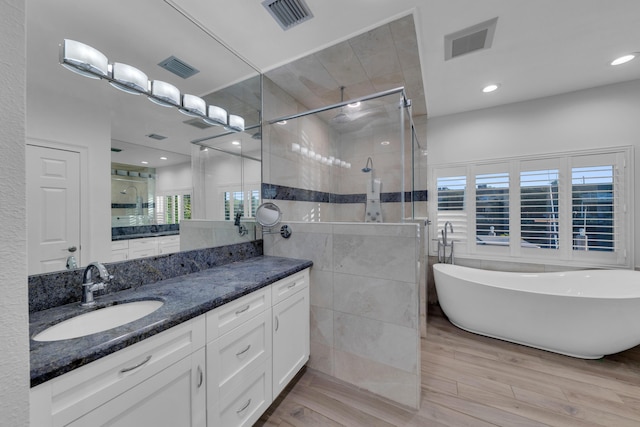 bathroom featuring shower with separate bathtub, wood-type flooring, tile walls, and vanity