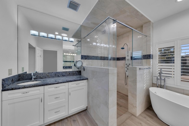 bathroom featuring shower with separate bathtub, hardwood / wood-style floors, vanity, and tile walls