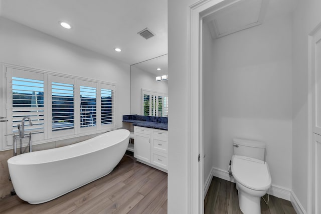 bathroom featuring vanity, hardwood / wood-style floors, a bathtub, and toilet