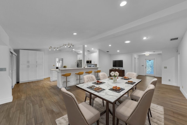 dining space with light hardwood / wood-style flooring and vaulted ceiling with beams