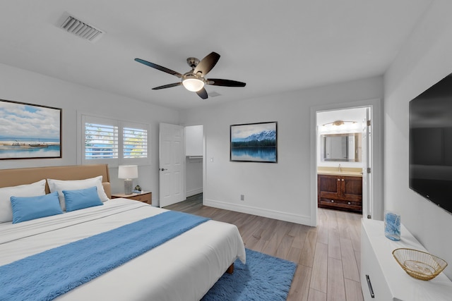 bedroom with ceiling fan, sink, ensuite bath, and light wood-type flooring