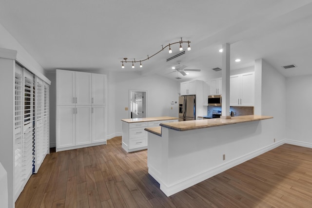 kitchen with light hardwood / wood-style flooring, stainless steel appliances, white cabinets, vaulted ceiling, and kitchen peninsula