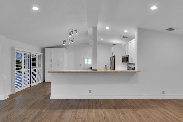 kitchen featuring stainless steel appliances, dark hardwood / wood-style floors, white cabinets, and kitchen peninsula