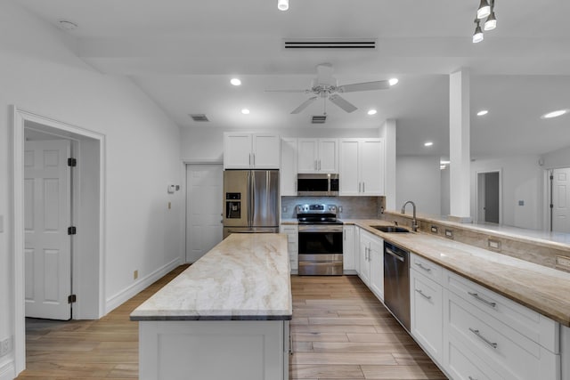 kitchen with sink, appliances with stainless steel finishes, white cabinetry, light stone countertops, and kitchen peninsula