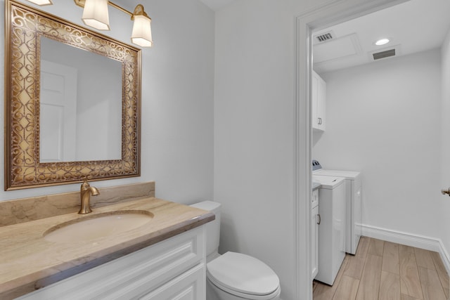 bathroom with vanity, toilet, washing machine and dryer, and hardwood / wood-style floors