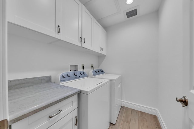 laundry room featuring separate washer and dryer, cabinets, and light wood-type flooring