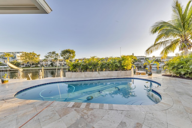 view of swimming pool featuring a patio and a water view