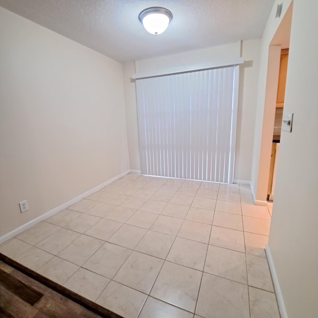 spare room featuring a textured ceiling and light tile patterned flooring