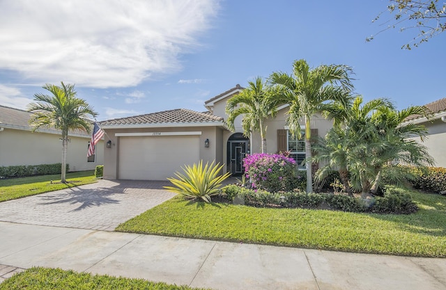 view of front of home featuring stucco siding, a tile roof, an attached garage, decorative driveway, and a front yard