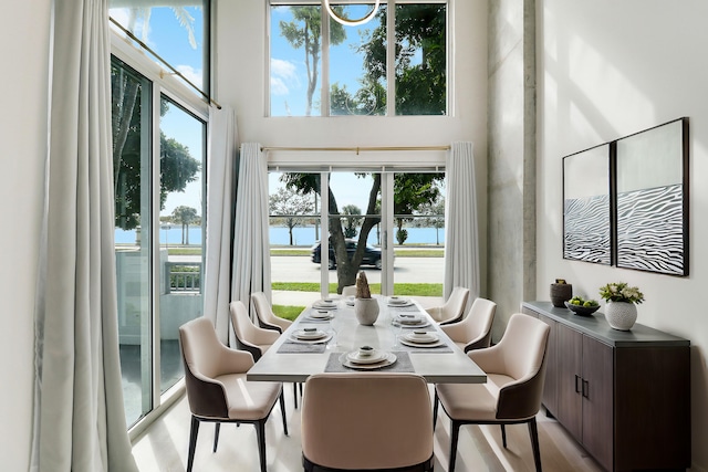 dining area featuring a water view and a towering ceiling