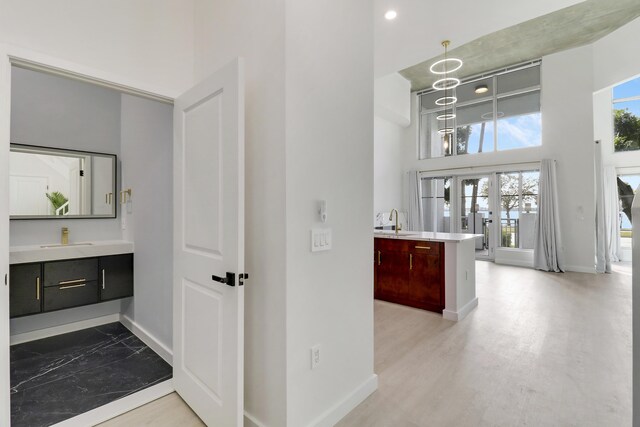 interior space with vanity, wood-type flooring, a towering ceiling, and french doors