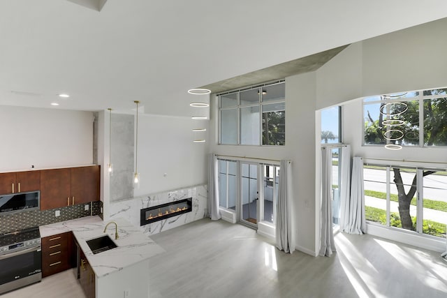 kitchen featuring sink, oven, a high ceiling, light stone counters, and a high end fireplace