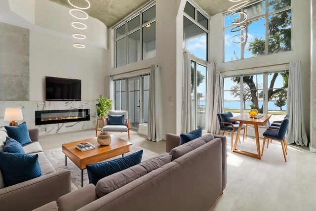 unfurnished living room featuring a high ceiling, wood-type flooring, a water view, and a high end fireplace