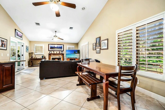 dining area with visible vents, ceiling fan, a lit fireplace, and light tile patterned floors