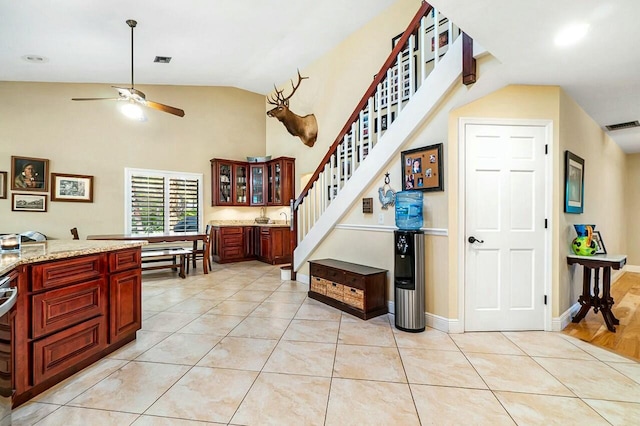 kitchen featuring light stone countertops, light tile patterned floors, visible vents, and glass insert cabinets