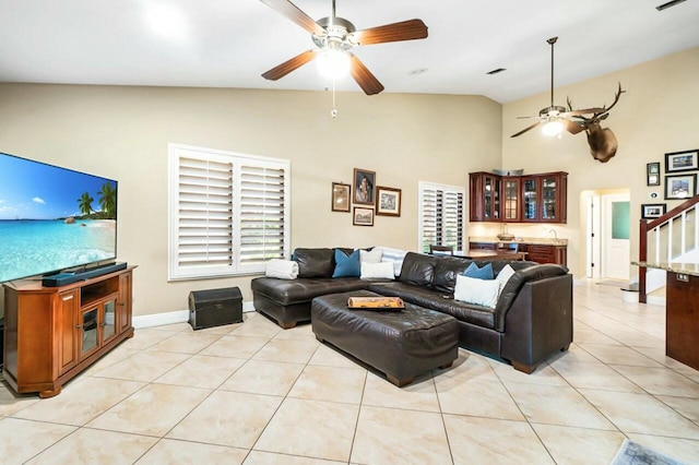 living area with light tile patterned floors, ceiling fan, indoor bar, visible vents, and stairs