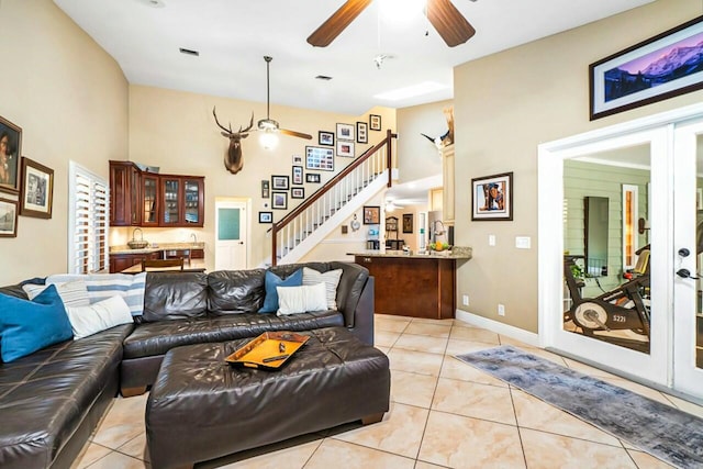 living area with ceiling fan, stairway, french doors, and light tile patterned flooring