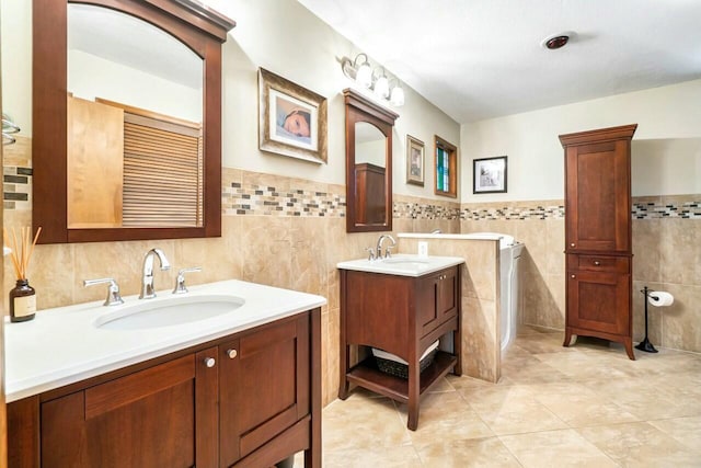 bathroom with two vanities, a sink, tile patterned flooring, and tile walls