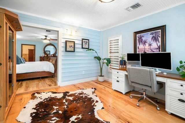 office area with baseboards, light wood-type flooring, visible vents, and crown molding