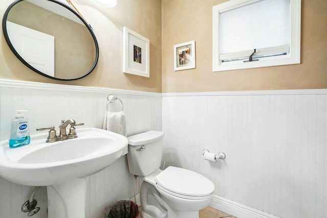 bathroom with a wainscoted wall, a sink, and toilet