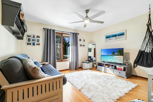 living area featuring baseboards, light wood-style flooring, and a ceiling fan