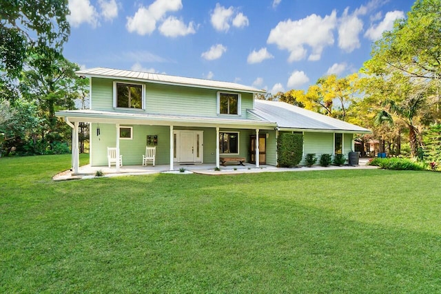 back of property featuring metal roof, cooling unit, and a yard