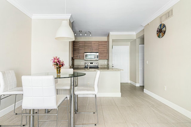 tiled dining space featuring ornamental molding and rail lighting