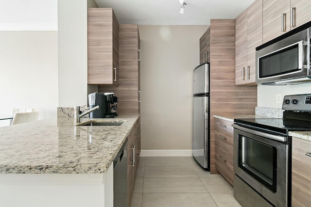 kitchen featuring sink, appliances with stainless steel finishes, light stone counters, light tile patterned flooring, and kitchen peninsula