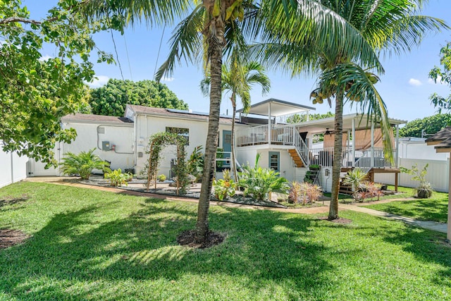 back of property with fence, a yard, ceiling fan, stairs, and roof mounted solar panels