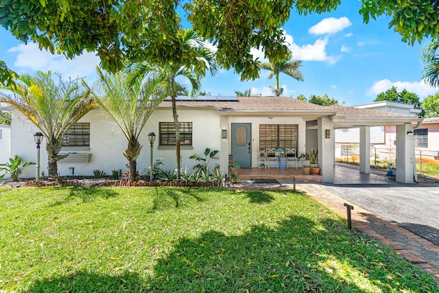 single story home with a front lawn, roof mounted solar panels, and stucco siding