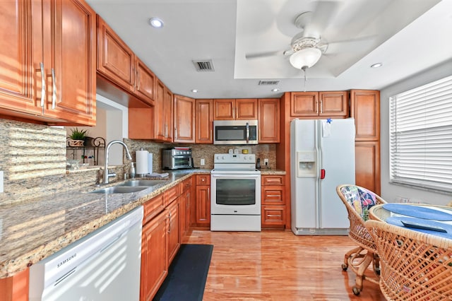 kitchen with sink, white appliances, ceiling fan, light stone countertops, and decorative backsplash