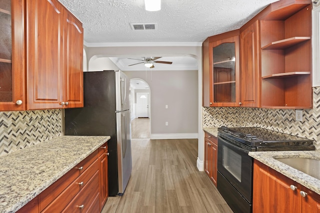 kitchen with ceiling fan, black electric range oven, light stone counters, and light hardwood / wood-style flooring